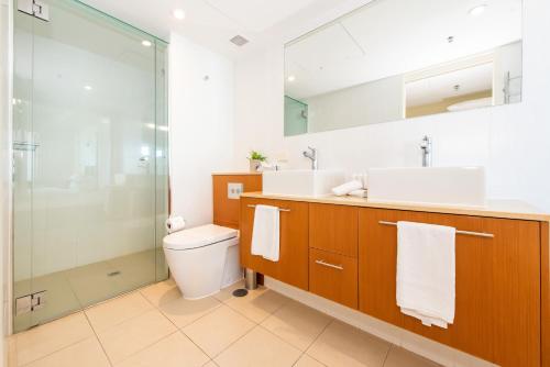 a bathroom with a toilet and a glass shower at Lanai Riverside Apartments in Mackay
