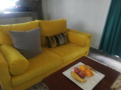 Kakamega的住宿－Casa nostra，一张黄色的沙发,桌子上放着一盘水果
