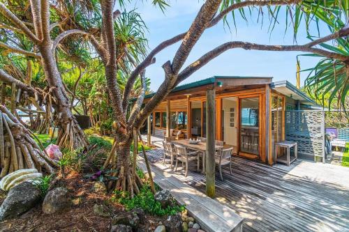 a house on the beach with a wooden deck at Fuller Holidays - Belongil Beachside Cottage in Byron Bay