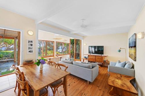 a living room with a table and a couch at Fuller Holidays - Belongil Beachside Cottage in Byron Bay