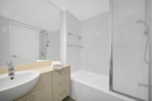 uma casa de banho branca com um lavatório e um chuveiro em Trilogy Residences Brisbane em Brisbane
