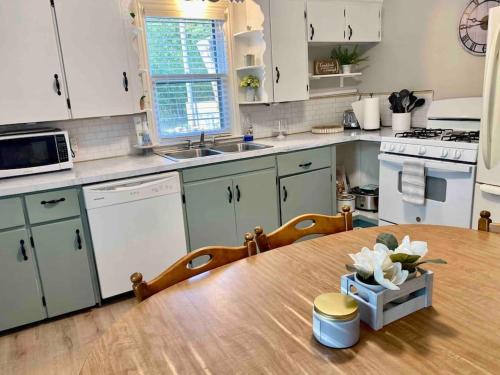 a kitchen with a wooden table and white appliances at Cozy Neutral Farmhouse, Coffee provided, Relaxation optional in Muskegon
