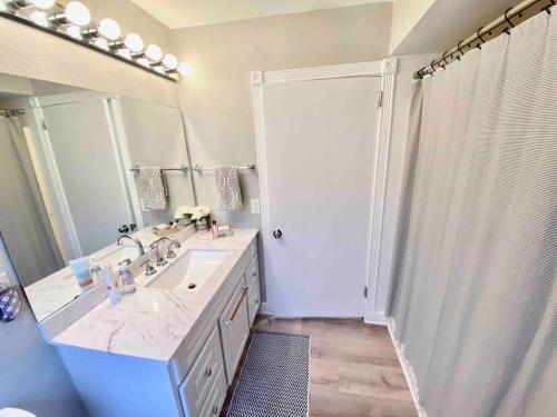 a bathroom with a sink and a shower with a mirror at Cozy Neutral Farmhouse, Coffee provided, Relaxation optional in Muskegon
