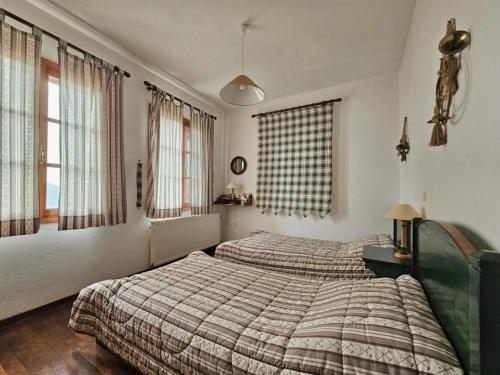 una camera da letto con due letti e due finestre di Duke's Horizon Villa in Arachova ad Aráchova