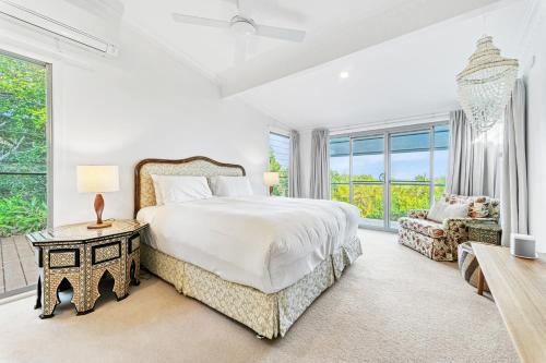 a white bedroom with a large bed and a couch at Lee Lane Beach House - Lighthouse Rd Byron in Byron Bay