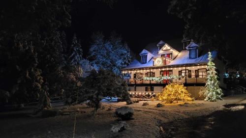 a house decorated with christmas lights and a christmas tree at Auberge La Châtelaine in La Malbaie