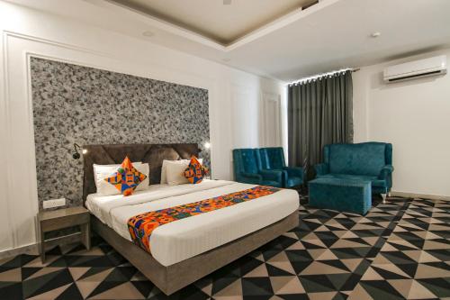 a hotel room with a bed and two blue chairs at FabHotel Signature Luxe Inn - Chhattarpur in New Delhi