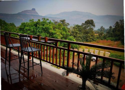 a balcony with two chairs and a view of mountains at ‘The Mountain Majesty’: cozy 1 bhk apartment in Karjat