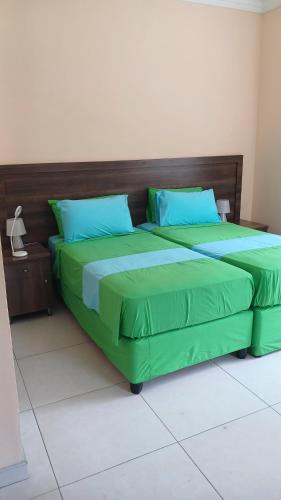 1 cama con sábanas verdes y almohadas azules en una habitación en Beau Bassin Inn, en Baie Lazare Mahé