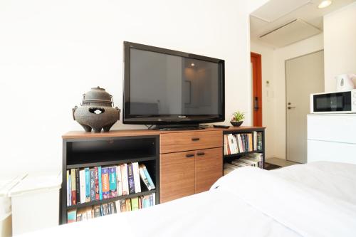 a bedroom with a tv on a dresser with a book shelf at Bird Hostel in Kyoto