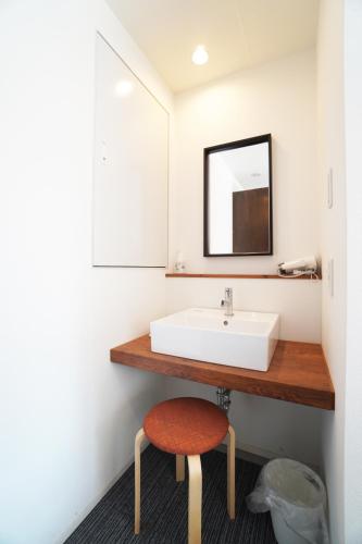 a bathroom with a sink and a stool under a mirror at Bird Hostel in Kyoto