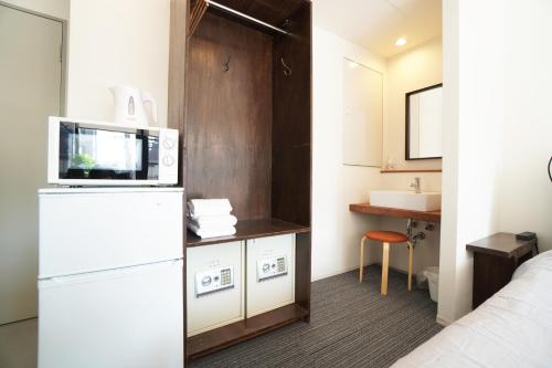 a small room with a white refrigerator and a sink at Bird Hostel in Kyoto
