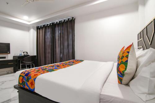 a white bed in a room with a desk at FabHotel Sky Suites Karkardooma in New Delhi