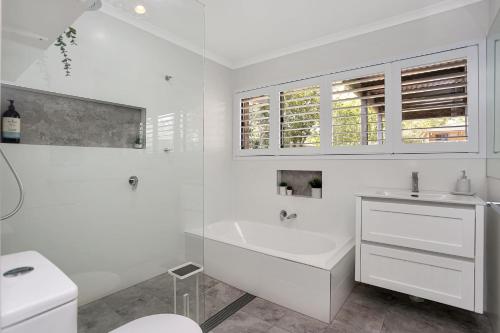 La salle de bains blanche est pourvue d'une baignoire et d'un lavabo. dans l'établissement Summer Bay Sunsets, à Hawks Nest