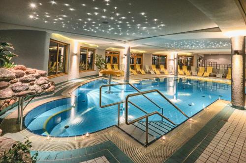 a large swimming pool in a hotel with yellow chairs at Family & Sporthotel Kärntnerhof in Bad Kleinkirchheim