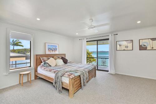 a bedroom with a bed with a view of the ocean at New Property Silverwater Serenity Shores Absolute Waterfront On The Lake in Bonnells Bay