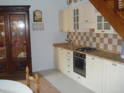 uma cozinha com armários brancos e um forno com placa de fogão em La Vigna Apartment em Siena