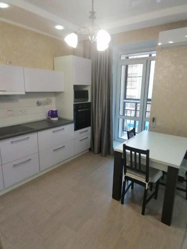 uma cozinha com armários brancos e uma mesa e cadeiras em City Centre Vip Apart em Tbilisi