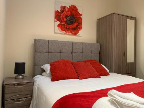 a bedroom with a large bed with red pillows at Market Place Serviced Apartments, Leek in Leek