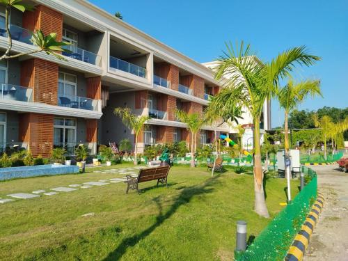un edificio con panchina e palma di fronte di Palm Resorts a Tinsukia