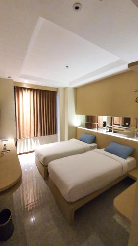 Habitación de hotel con 2 camas y sofá en MP Hotel Kelapa Gading en Yakarta