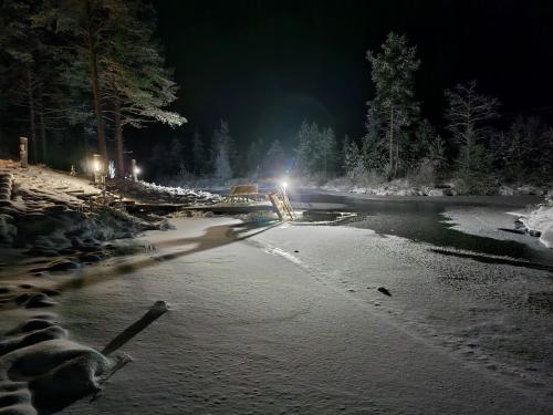 a night time picture of a river with snow and trees at Villa Kanger in Kuusamo