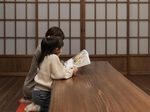 a woman and a child sitting on a table reading a book at moku杢 in Miyazu