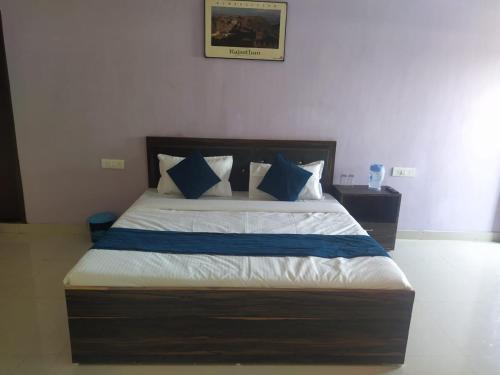 1 dormitorio con 1 cama con almohadas azules y blancas en Hotel Ghirdharval Near Maa Trikuta Temple-Kunhadi-Kota, en Kota