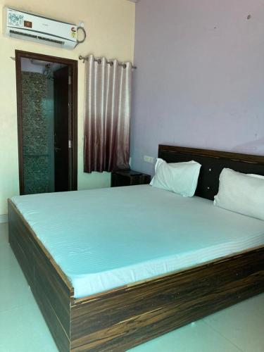 1 dormitorio con 1 cama grande con marco de madera en Hotel Ghirdharval Near Maa Trikuta Temple-Kunhadi-Kota, en Kota