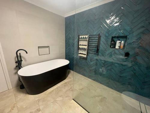 y baño con bañera y ducha acristalada. en Gorgeous apartment - pet friendly, stunning views, en Bridgetown