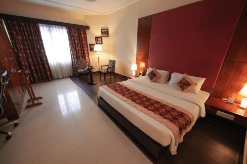 a bedroom with a large bed with a red wall at The South Park Hotel in Trivandrum