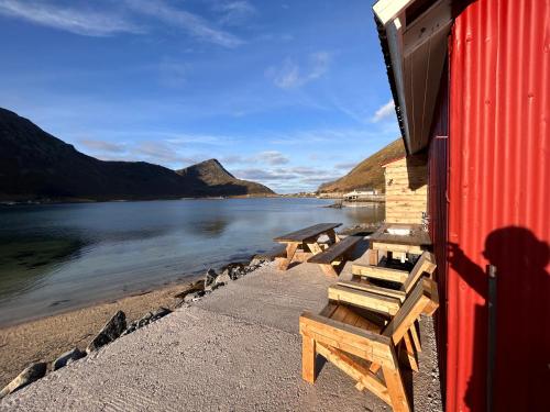 a couple of benches sitting on a beach next to a building at Casa Lofoten Ramberg Beach Sauna Surfing Kvalvika Reine in Ramberg