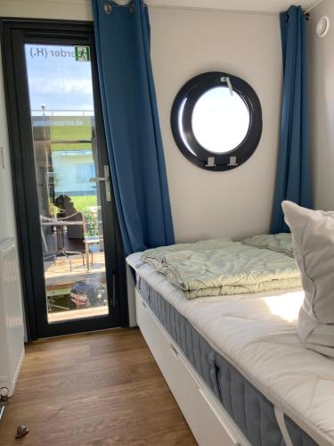 a bedroom with a window and a bed with blue curtains at Hausboot Celina in Werder