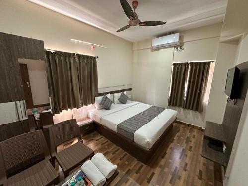 バンガロールにあるHotel JP Grandのベッドとテレビ付きのホテルルーム