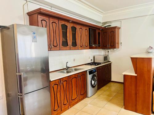 uma cozinha com armários de madeira e um frigorífico de aço inoxidável em Deluxe apartment in the city center em Yerevan