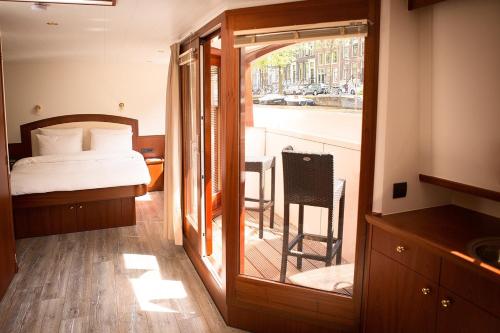 ein Schlafzimmer mit Bett und Blick auf einen Balkon in der Unterkunft Prinsenboot in Amsterdam