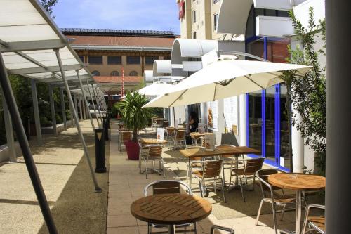 an outdoor patio with tables and chairs and umbrellas at ibis Marseille Centre Gare Saint Charles in Marseille