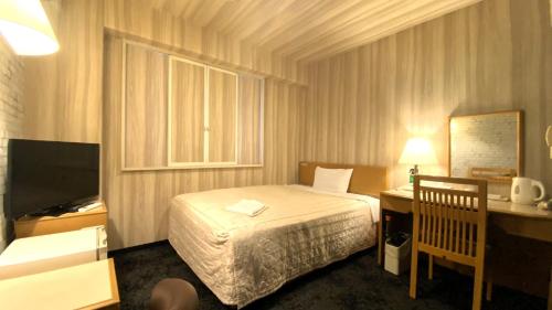 Habitación de hotel con cama, escritorio y TV. en Hotel Select Inn Isehara en Isehara