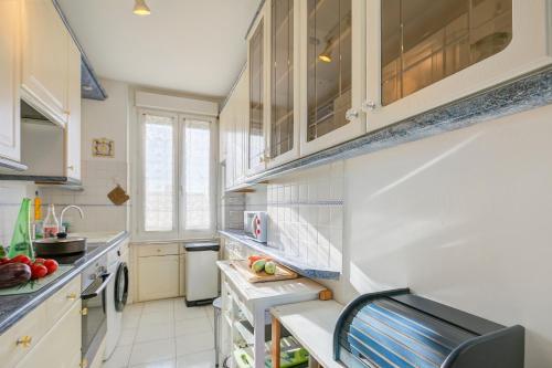 une petite cuisine avec des armoires blanches et un évier dans l'établissement Le 44 Antibes - Sea & Mountain View - Happy Rentals, à Antibes