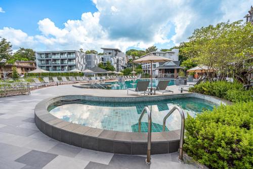 een zwembad in een resort met stoelen en een gebouw bij Orchidacea Resort - Kata Beach in Kata Beach