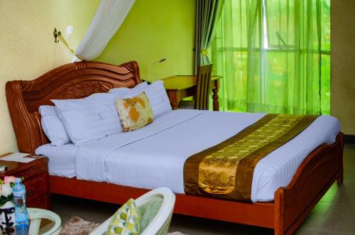 a bedroom with a large bed with white sheets and a window at La Grande Hotel in Kampala