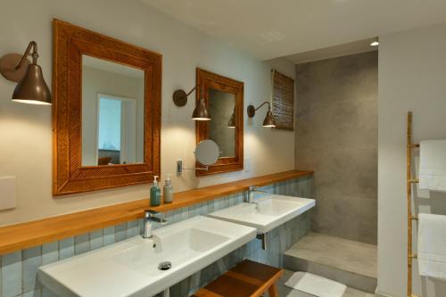 a bathroom with two sinks and two mirrors at Veranda Grand Baie Hotel & Spa in Grand Baie