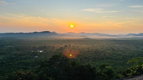 a sunset over a forest with the sun setting in the background at Village feel home stay in Sigiriya