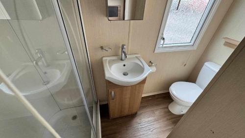 a bathroom with a sink and a shower and a toilet at 8 BERTH Deluxe caravan PALM GROVE 142 GOLDEN PALM CHAPEL ST LEONARDS in Chapel Saint Leonards