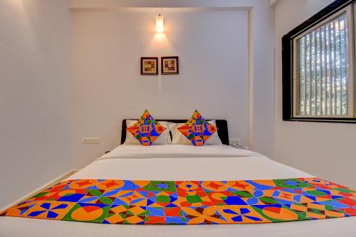 1 dormitorio con 1 cama con un edredón colorido en FabExpress Sky Inn en Pune