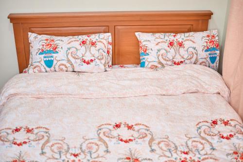 1 cama con edredón rosa y 2 almohadas en Kilimanjaro poa, en Moshi