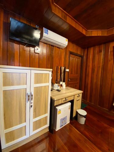 a kitchen with a white cabinet and a tv on the wall at Ruan Mai Naiyang Beach Resort in Nai Yang Beach