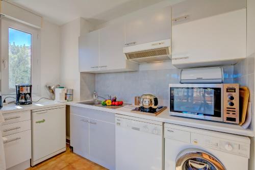 une cuisine avec des armoires blanches et un micro-ondes dans l'établissement Cap et Soleil - Happy Rentals, à Antibes