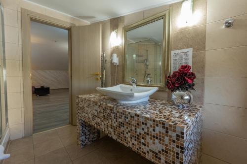 een badkamer met een wastafel op een aanrecht met een bloem bij Hotel Corvaris in Boekarest