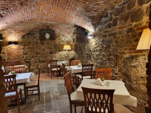 モンテ・サン・サヴィーノにあるHotel Logge Dei Mercantiのレンガの壁にテーブルと椅子が並ぶレストラン